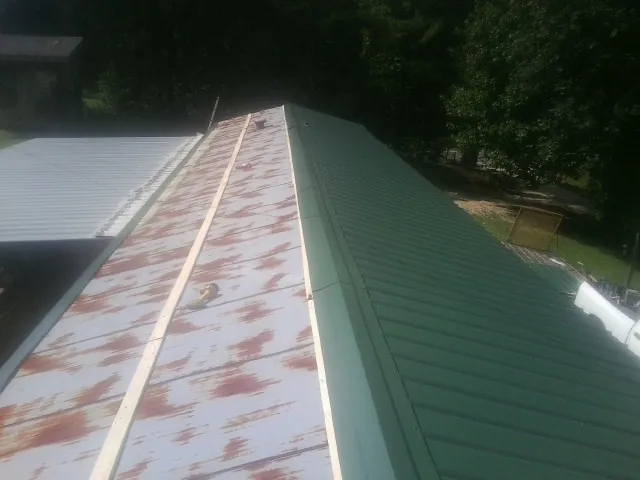 Old rusted panels beside newly installed green metal roofing — Wind Damage Roof Repair by Roofing Brothers in Albuquerque