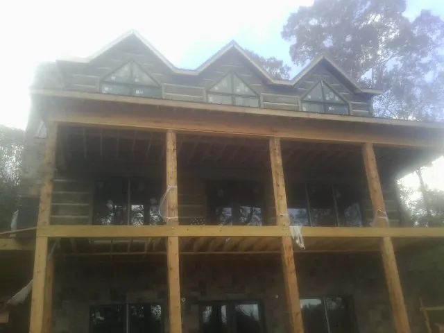 Dormers and porch framing on a large log home under construction — Roof Coating work by our crew in Albuquerque