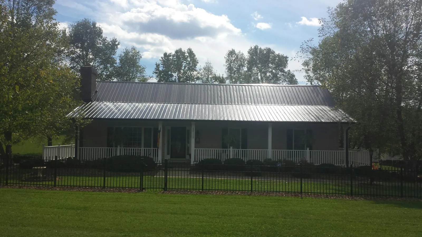 Gray metal roof on a brick ranch with a full width front porch — Gutter Guard Installation work by our crew in Albuquerque