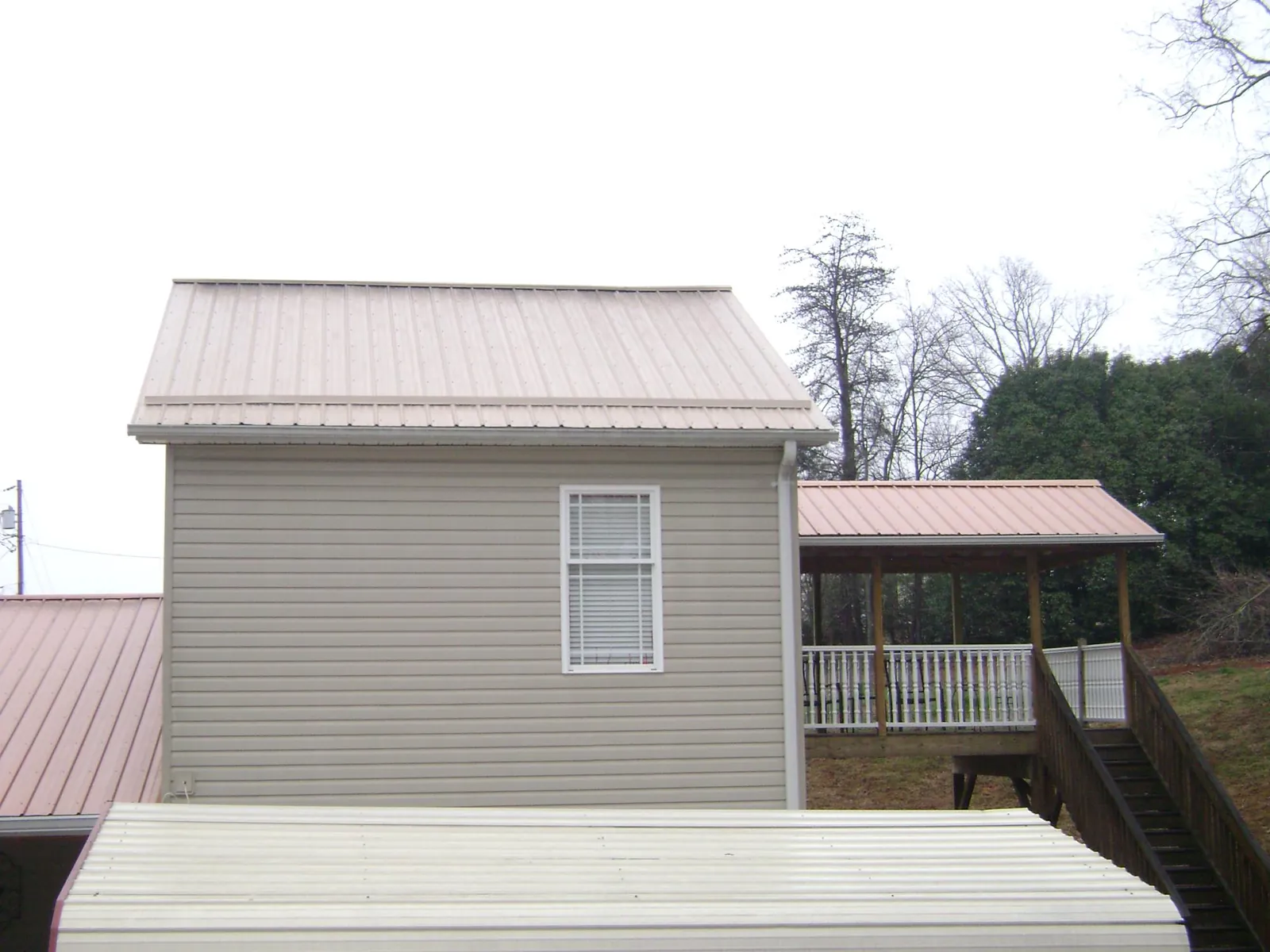 Tan metal roofs on a two story addition and attached porch, from a Roof Replacement job in Albuquerque